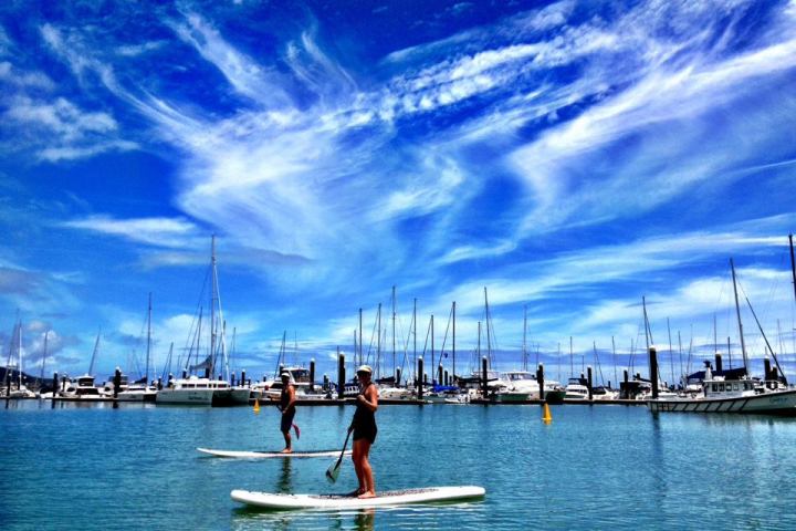 Two people on SUPs with the marina in the background