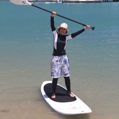 a Grandma on a SUP with her paddle raised high in the Whitsundays